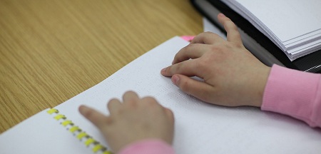 Das Bild zeigt die Hände eines Kindes beim Lesen von Brailleschrift