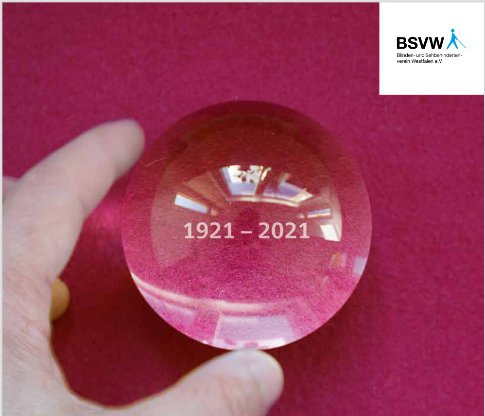Motiv vom Titelblatt der BSVW-Festschrift: Zwei Finger halten eine kleine Glaskugel, in der steht: 1921 – 2021