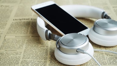 Das Foto zeigt ein Smartphone und Kopfhörer, die auf einer Zeitung liegen. Quelle: Pixabay