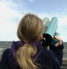Junge Frau mit Fernglas am Meer